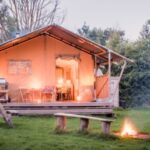 The Jenny Wren safari tent lit up at dusk with a fire pit