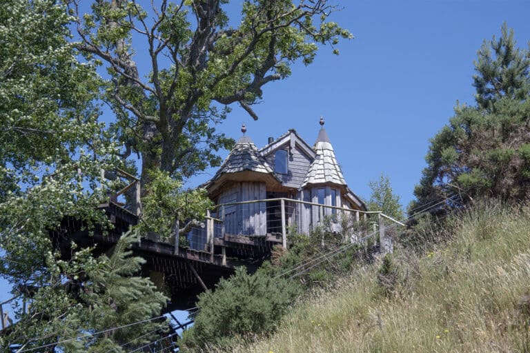 Turreted timber treehouse on stilts among oak trees, Craighead Howfs, Perthshire