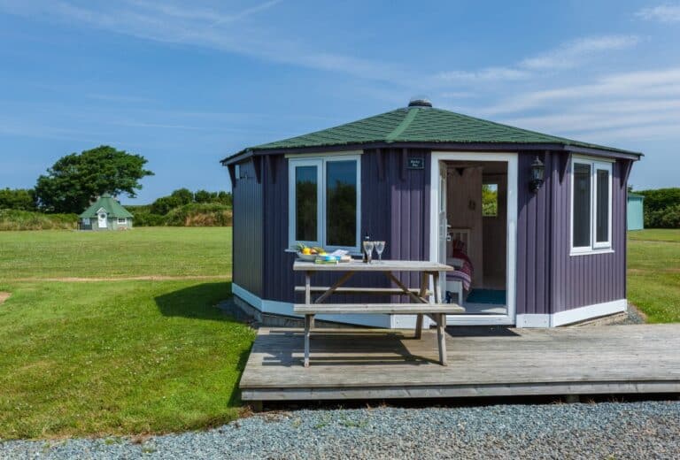 Purple timber cabin with a private deck and picnic bench at Coastal Cabins, Hartland, North Devon