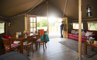 Safari tent interior with a dining table and sofa opening to the valley view