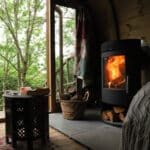 Wood-burning stove lit beside open doors onto a woodland deck, Coplow Woodland Retreat
