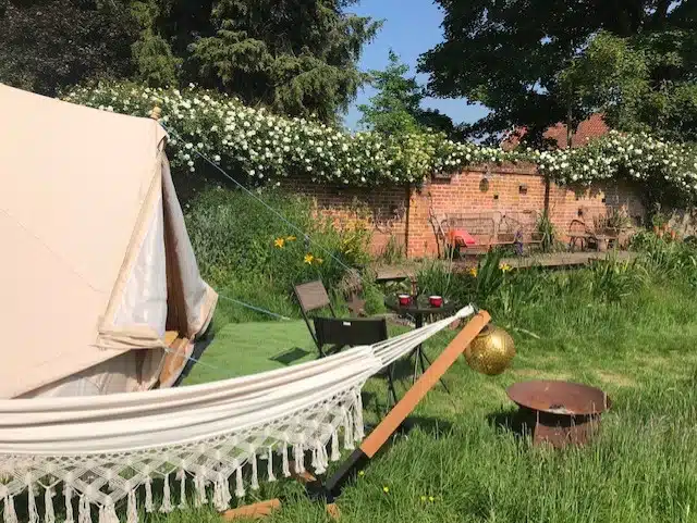 Bell tent with hammock in a walled garden with climbing roses