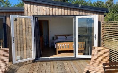 Timber cabin with open doors showing a double bed, Little Halden Farm, Kent