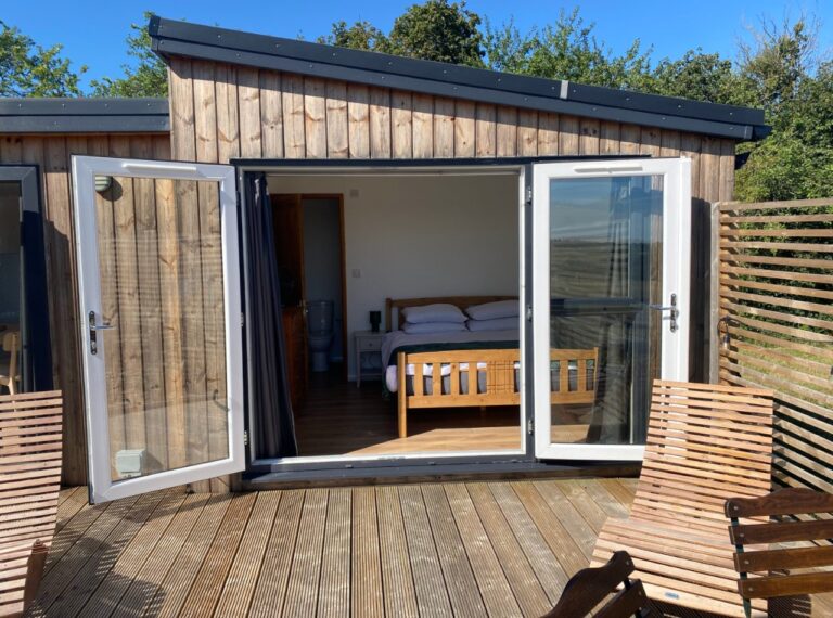 Timber cabin with open doors showing a double bed, Little Halden Farm, Kent