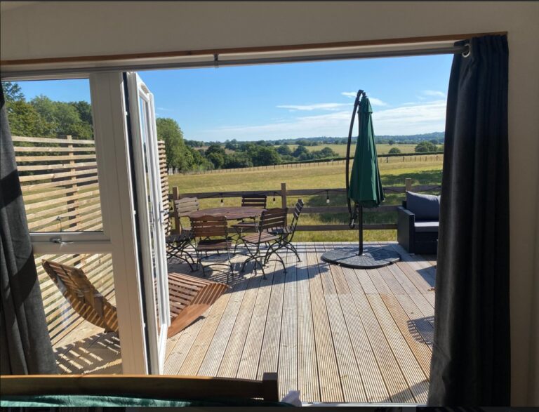 Open French doors from the cabin onto the deck with the countryside view beyond