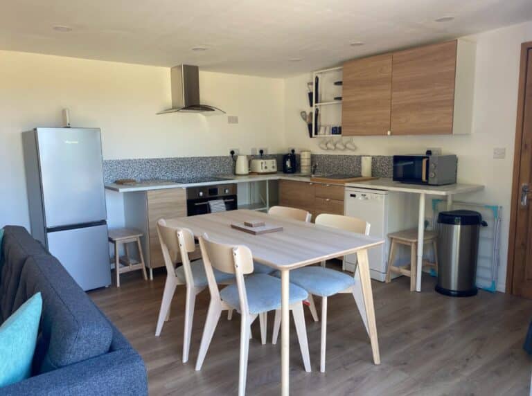 Kitchen-diner with a white dining table, fridge, units and an extractor