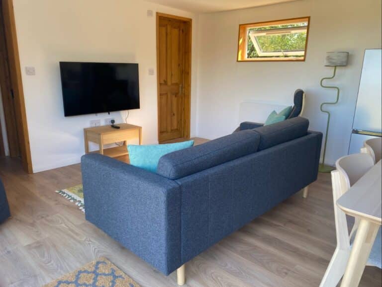 Cabin living area with a blue sofa, a wall-mounted TV and a wood floor