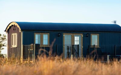 Navy shepherds hut in long grass overlooking the Brecon Beacons, Powys