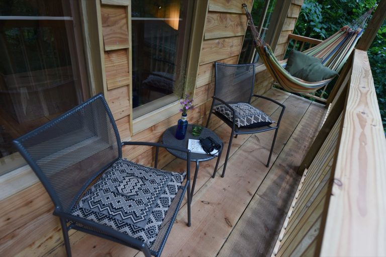 Balcony of the Treetop Cabin with hammock, chairs and table, looking into the woodland canopy