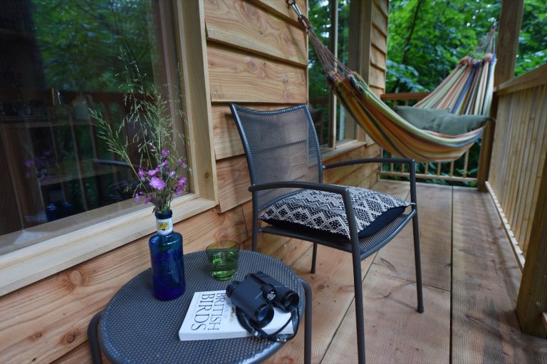 Seating on the Treetop Cabin balcony, with views across the wooded valley