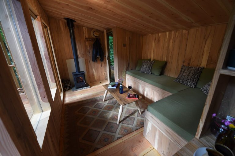 Living area of the Treetop Cabin with bench seating and a log burning stove