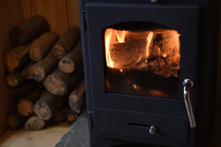 The log burning stove lit inside the Treetop Cabin at Redwood Valley, with wood provided