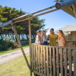 Family on veranda of a safari tent at Ruda Holiday Park in Croyde Bay