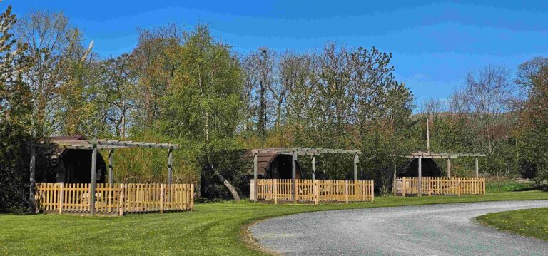 View of 3 Glamping pods at Meadow Falls. All nicely spaced with gravel terraces and pickett fences.