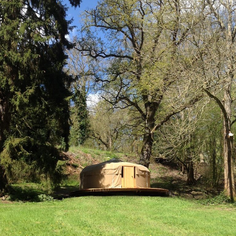 A yurt at Redwood Valley glamping, Presteigne, Powys, sitting on the meadow in bright sunshine