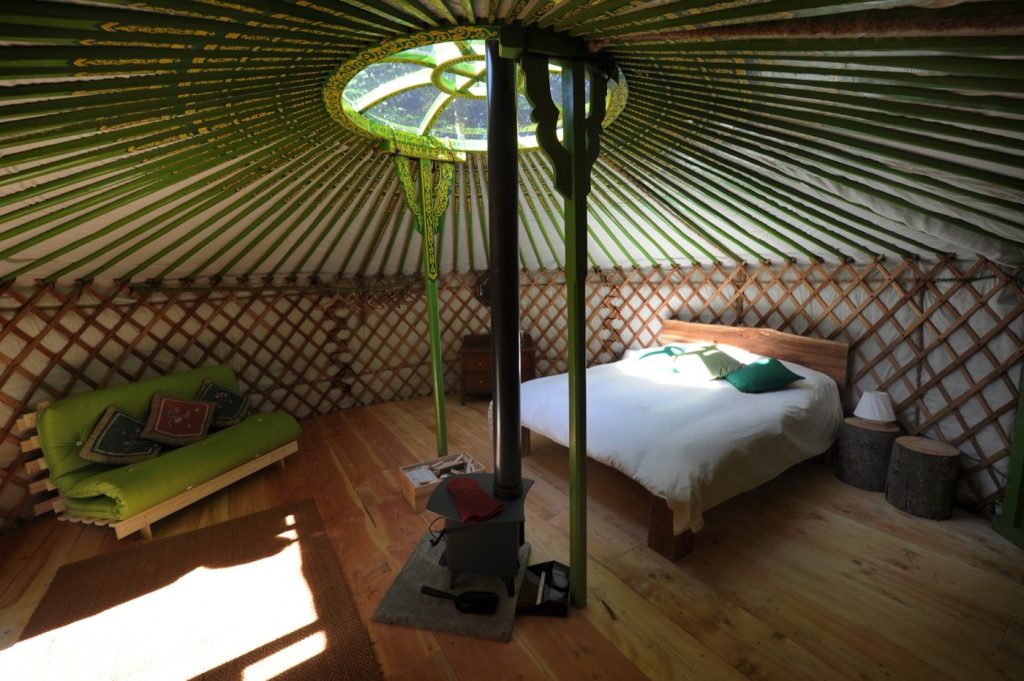 Inside a 19ft yurt at Redwood Valley, with log burner, bed and the crown wheel above