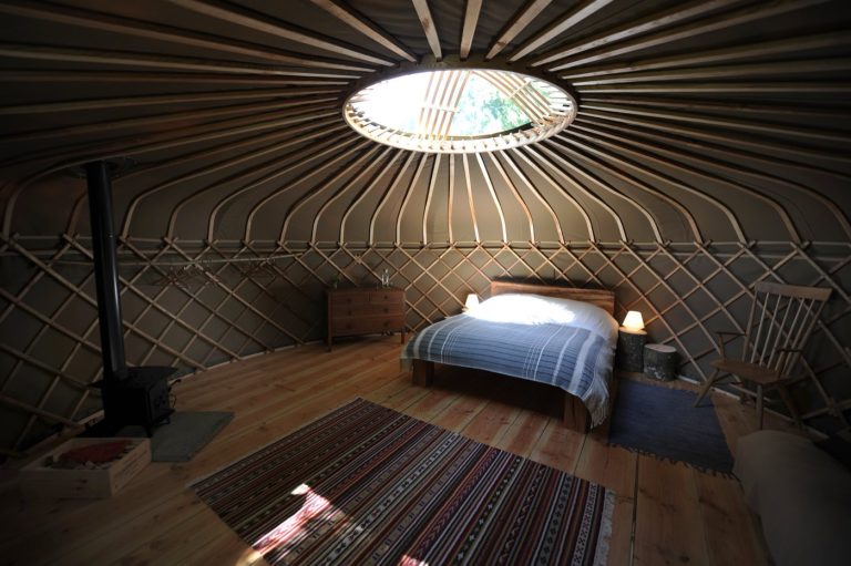 Yurt interior at Redwood Valley glamping with king size bed and log burning stove