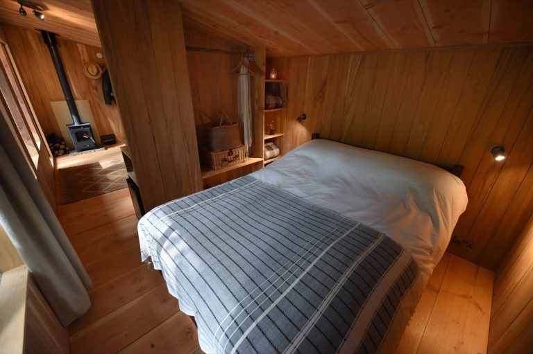 Inside the Treetop Cabin at Redwood Valley, with its timber walls and double bed