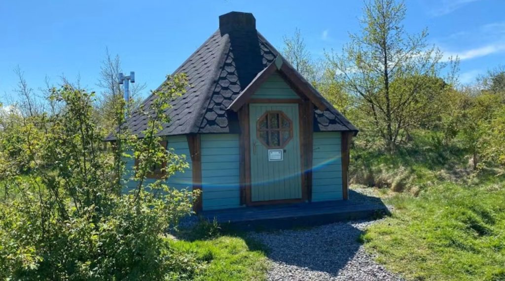Green Scandinavian-style eco cabin with a pointed slate roof at Skye Eco Bells on the Isle of Skye