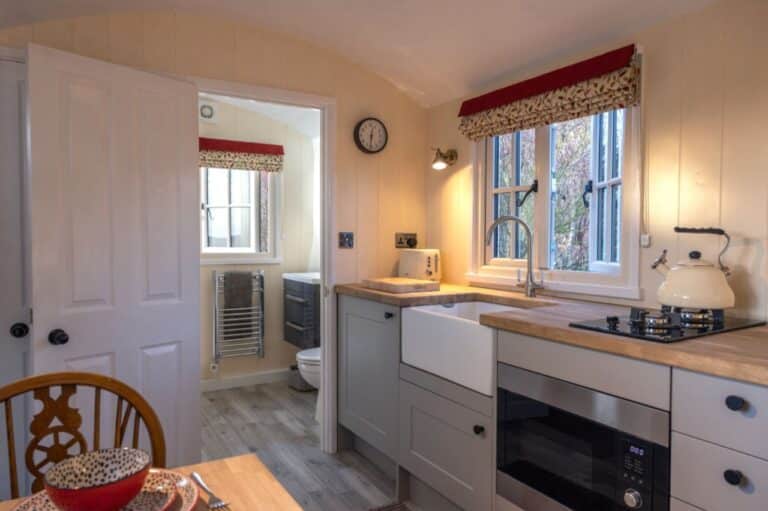 Shepherd's hut interior at Abbey Farm with Belfast sink kitchen and door to the shower room