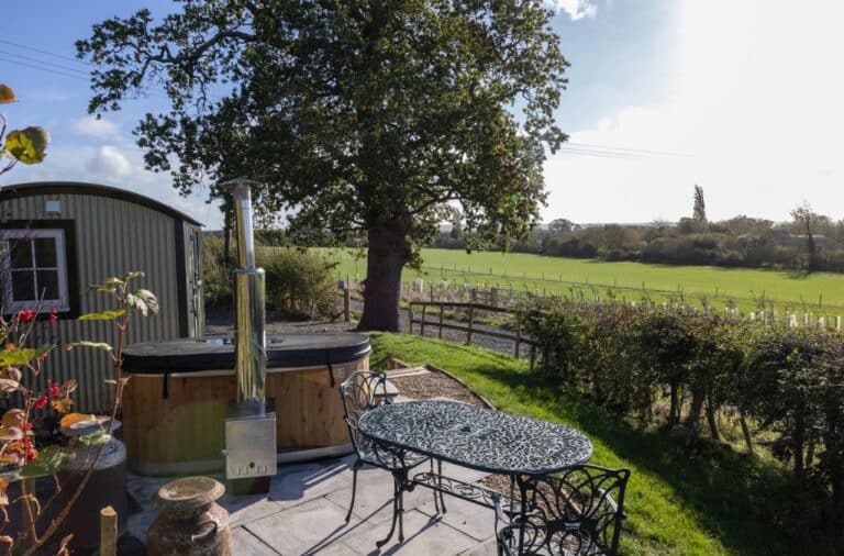 Shepherd's hut and wood-fired hot tub under an oak tree at Abbey Farm, with field views