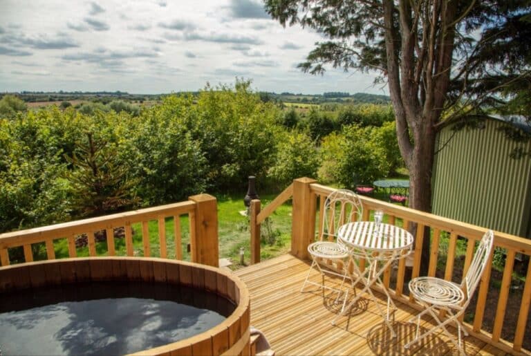 Wood-fired barrel hot tub and bistro table on the decked terrace at Abbey Farm, overlooking Chilterns countryside