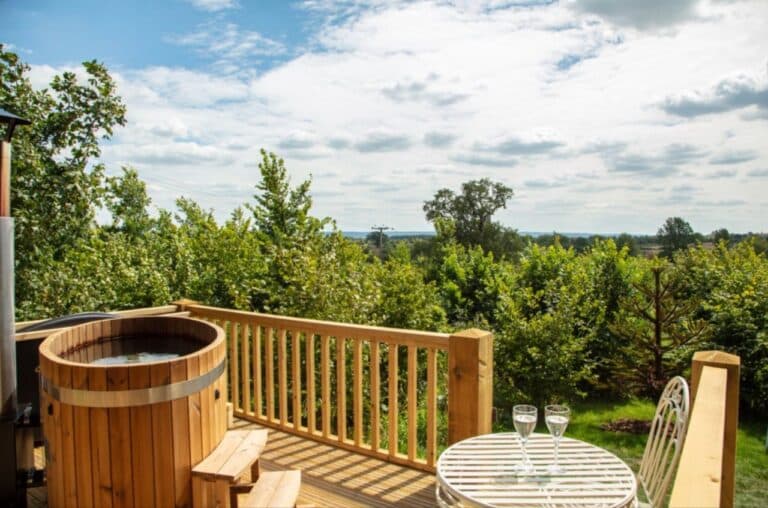 Wooden hot tub and table on the deck at Abbey Farm, with open views over the Oxfordshire countryside