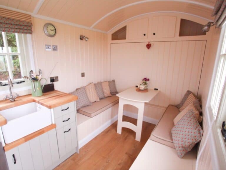 Inside an Abbey Farm shepherd's hut — Belfast sink kitchen and a cushioned corner dining seat