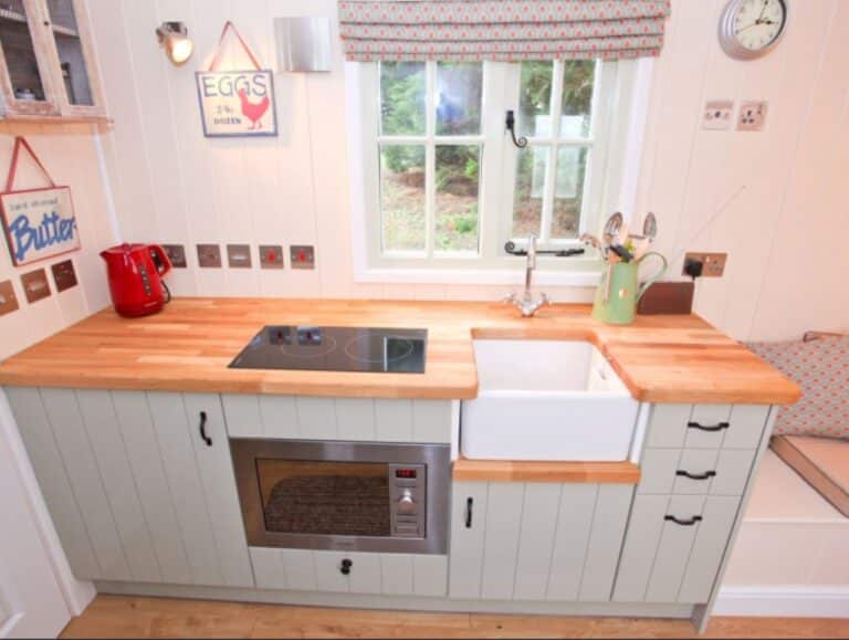 Shepherd's hut kitchen at Abbey Farm with induction hob, Belfast sink and a countryside window