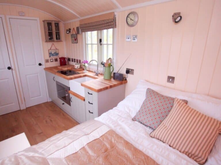 Kitchen and double bed inside a shepherd's hut at Abbey Farm in the Chilterns