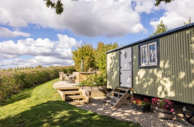 Green shepherd's hut and gravel terrace at Abbey Farm, beside a Chilterns cornfield