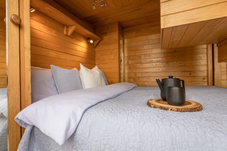 Timber-lined bedroom at Tinywood One with king size bed and morning tea